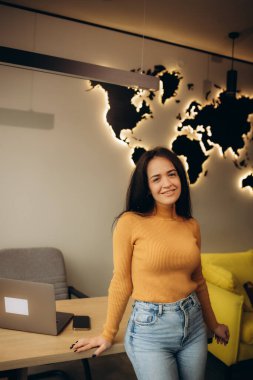 Seyahat acentesinde bilgisayarında dinlenmek için en iyi otellerde çalışırken kameraya bakan kadın turist temsilcisi. Tatil, turizm ve seyahat. Seyahat rezervasyonu. 