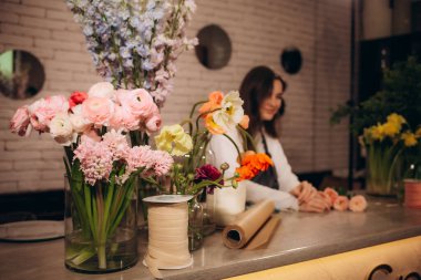 Çiçekçide bir kadın çiçekçi bir buket çiçek yapar.