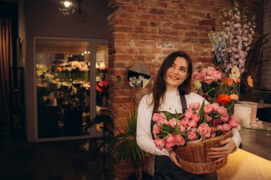 Kameraya bakan kırmızı laleli genç bayan çiçekçinin portresi. Yüksek kalite fotoğraf