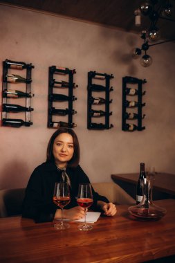 Genç kadın şarap uzmanı mahzende oturan adamın rengine bakarak kırmızı şarap üzerinde çalışıyor. Şarap kursunda şarap içen kadın şarap garsonu..