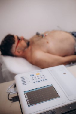 Cihaz ya da cihaz bir doktorun ofisindeki elektrokardiyogramın ölçüm birimidir. Hastanedeki erkek hastada EKG elektrokardiyogramı var. seçici odak