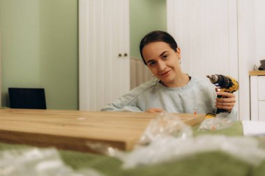 Kadınlar sandalye bacağını tamir etmek ve mobilya montajı için tornavida teçhizatıyla vidaları sıkılaştırıyor.