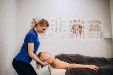 Emekli bir kadın masaj için rehabilitasyon terapistine gider.