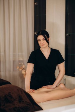 Professional caucasian specialist is doing leg message at modern minimalistic salon clipart