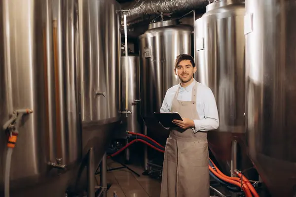 stock image Handsome bearded man brewer inside modern beer factory around steel tanks