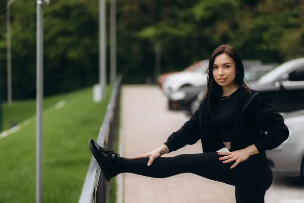 stock image view on woman warming up her muscles and leans with one foot on the fence while stretching the other leg. Copy space