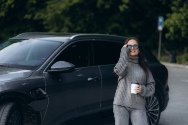 Güzel başarılı Avrupalı kız şehirdeki şarj istasyonunda elektrikli cipini şarj ediyor. Elektrikli araba, geleceğin ulaşım aracı..