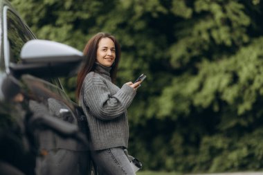 Kadın elektrik santralinde jipini şarj ediyor.