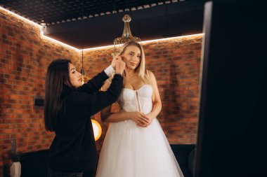 beautiful caucasian woman try on future wedding dress made by designer in her own salon, look at dress with love, dream