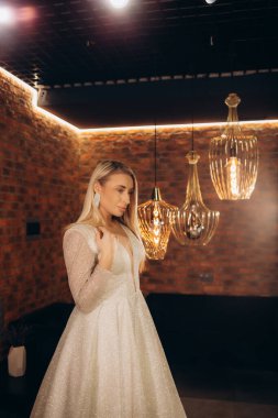 gülümseyen güzel gelin beyaz cüppe düğün moda dükkanında seçer