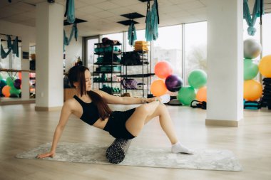 Fitness, physio massage and woman with roller on floor for leg tension and support in yoga workout at gym. Health, pilates and massaging for sports physiotherapy, girl on ground foam rolling muscle.