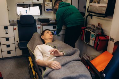 Ambulansta bir kadına yardım ediliyor.