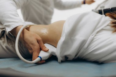 Doktor klinikte kadının ultrason muayenesi yapıyor.