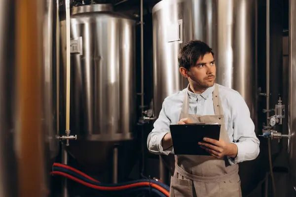 stock image man at brewery taking notes on brewing process