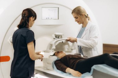 Doktorlar hastayı MRI tanı merkezinde tam vücut tarama prosedürüne hazırlıyorlar..