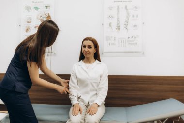 Kadın doktor ve hastası birlikte tablete bakıyor ve teşhis, tedavi, ilacın yan etkisi, hastaların hastalık geçmişi ve analizleri tartışıyorlar..