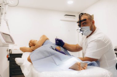 Doktor ve hemşire estetik tıp kliniğinde dermatolojik ameliyatın kaldırılması sırasında...