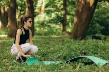 Genç bir kadın sabah egzersizden önce yoga minderi seriyor. Yoga öğretmeni dışarıda..