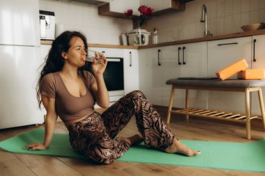 a woman in the kitchen drinking vodka after sports clipart