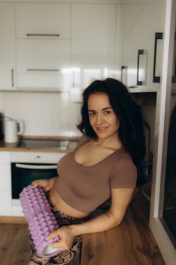 Mutfakta yoga silindirli bir kadın var.