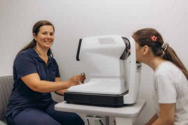 Yarık lamba kullanan çocuğun incelenmesi. Mikroskop ve odaklanmış ışık kaynağı. Merceğin durumunu belirlemek için gözün yüksek hassaslıkta incelenmesi için bir cihaz..