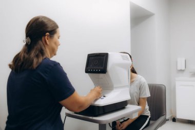 Yarık lamba kullanan çocuğun incelenmesi. Mikroskop ve odaklanmış ışık kaynağı. Merceğin durumunu belirlemek için gözün yüksek hassaslıkta incelenmesi için bir cihaz..