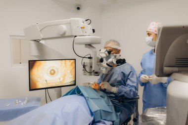 Yetenekli cerrah ve tıbbi ekibi yaşlı bir hastaya hassas bir göz ameliyatı yaparak en son tıbbi teknoloji ve ileri teknoloji ile görme yetisini geri kazandırıyor. Modern göz ameliyatı konsepti.