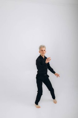 Siyah giyen bir adam beyaz arka planda salsa, zouk, kizomba yapar. 