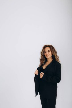 Beyaz arka planda siyah takım elbiseli bir kadın.