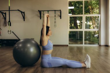 Çekici a kırılmak spor salonunda pilates topu bir şişe su ve enerji oturan genç bir kadın içki