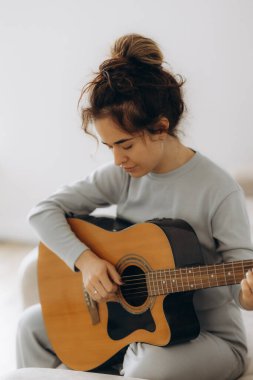 Genç Asyalı güzel bir kadının portresi gitar çalıyor, şarkı söylüyor ve yatak odasında dans ediyor. Gülümse mutlu Asyalı kız bilgi eğitimi kadın yaşam tarzı, okul konseptine geri dön.