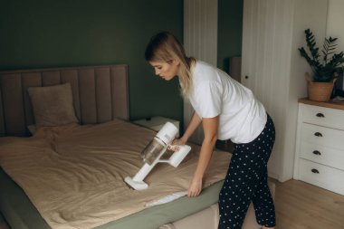 Yatak odasındaki yatağı süpüren kadın.