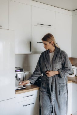 Bornozlu bir kadın kahve yapar.