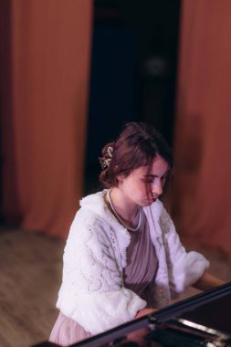 Klasik mükemmellik. Zarif bir odada piyano çalan güzel bir genç kadının fotoğrafı..