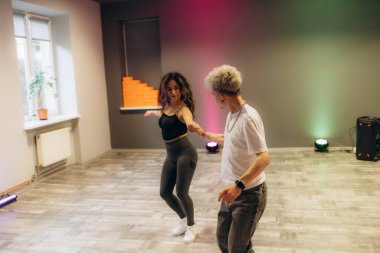 Pozitif genç çift diğer dans kurslarına katılanlarla birlikte tango dansı yapıyor.