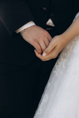 Gelin ve damat düğün günlerinde el ele tutuşur ve güneşli bir günde birbirlerine yüzüklerini takarlar. Ve turuncu güneş ışığı saçlarında parlıyor.