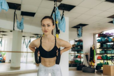 Genç, zayıf vücut formundaki kız spor salonunda sinek yogası yapıyor.