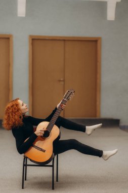 Evinde gitar çalan rahat bir kızıl kadın.