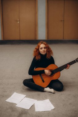 Kızıl saçlı bir kadın gitar çalışıyor.