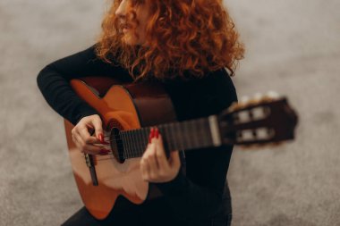 Kanepede oturmuş gitar çalan güzel, gülümseyen bir kadın.