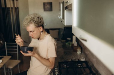 Mutfaktaki açık mermer masada leziz domates çorbası içen adam.