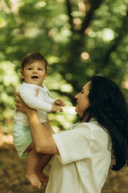 Bir anne oğluyla yürür ve onu bir yaz parkında kollarına alır.