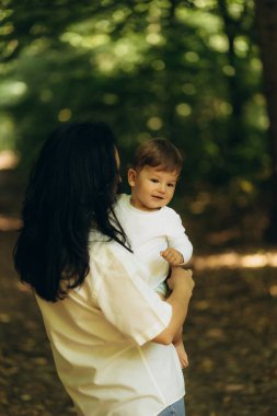 Bir anne oğluyla yürür ve onu bir yaz parkında kollarına alır.