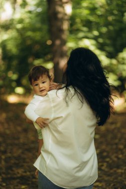 Bir anne oğlunu bir yaz parkında kollarına alır.