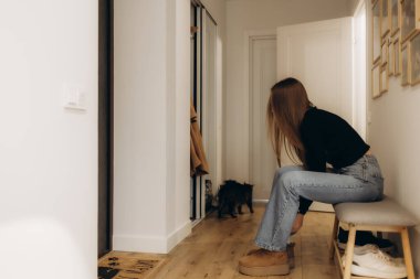 Bir kadın ayakkabılarını bir apartmanın koridorunda giyiyor.