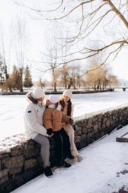 Aile, kış tatilinde birlikte dışarıda vakit geçirir. Kar yağdırır, güler, sevinir.