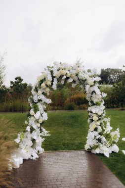 Çiçekli düğün kemeri açık havada güneş ışığında.