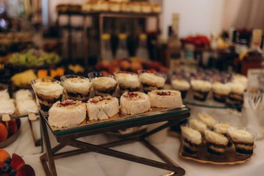 Bir masa dolusu tatlı ve beyaz masa örtüsü olan bir içecek. Tatlılar, onları sergileniyormuş gibi gösterecek şekilde düzenlenmiş. Sahne kutlama ve davetkar.