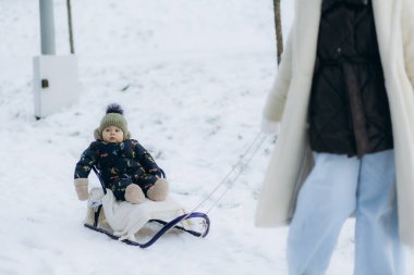  Boy sledding in a snowy forest. Outdoor winter fun for Christmas vacation. clipart