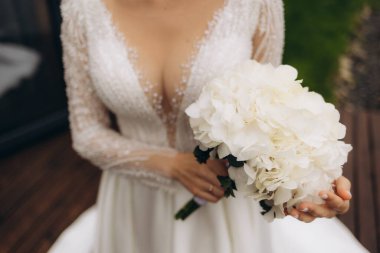 Beyaz elbiseli gelin elinde bir buket taze çiçek tutuyor. Gelinin buketi..